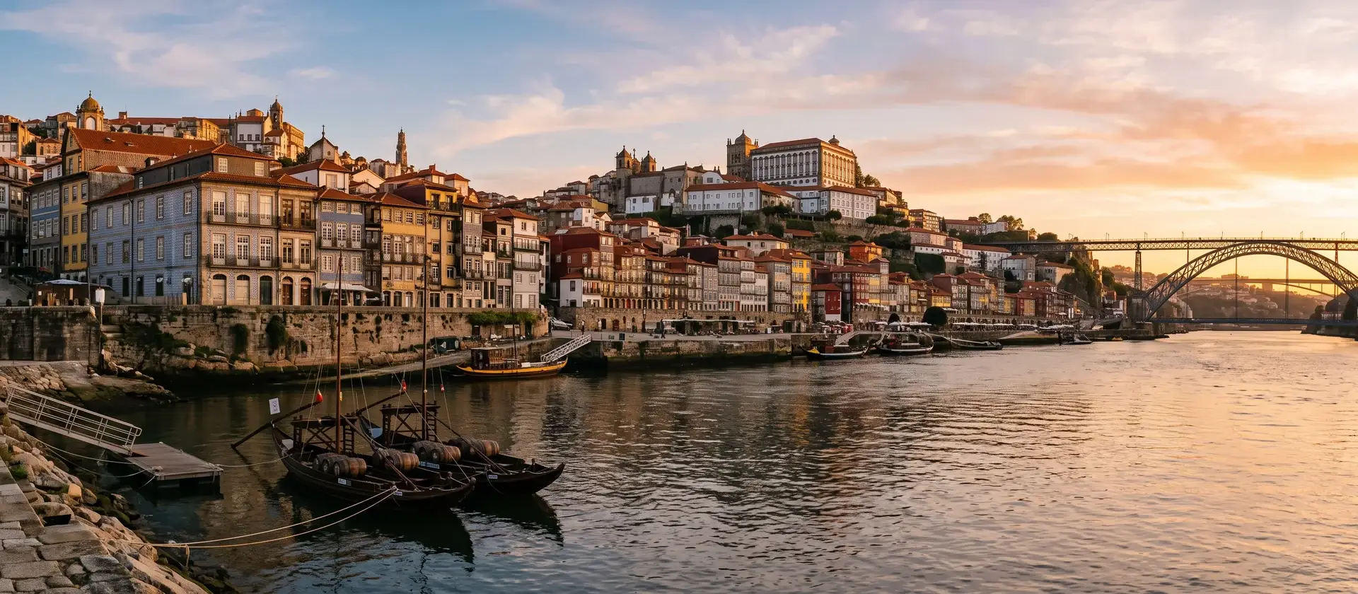Edificios de apartamentos sobre la ladera de una ciudad portuguesa junto a un río, con fachadas de azulejo y tejados de teja al atardecer