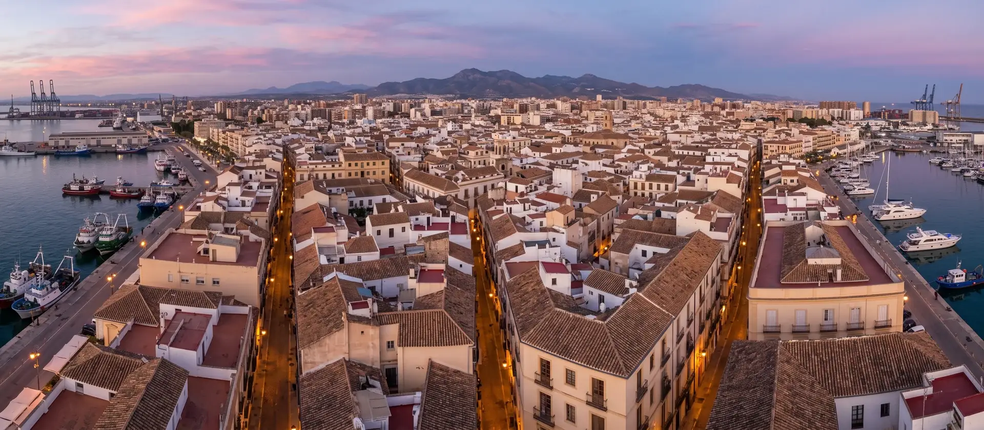 Tejados y fachadas del centro de una ciudad portuaria andaluza al atardecer, imagen ilustrativa del debate sobre la moratoria de alojamiento turístico en Málaga