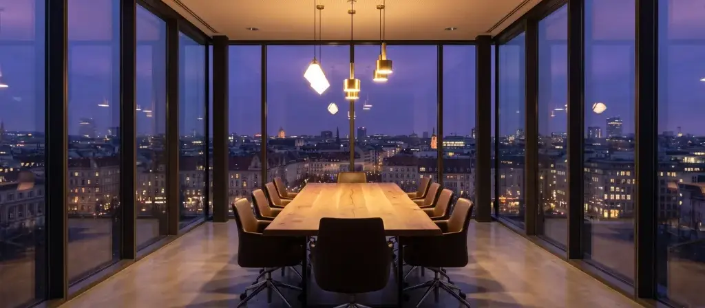 Sala de reuniones acristalada de una oficina contemporánea al atardecer con vistas a una ciudad europea, imagen ilustrativa de la captación de capital institucional para residencias de estudiantes