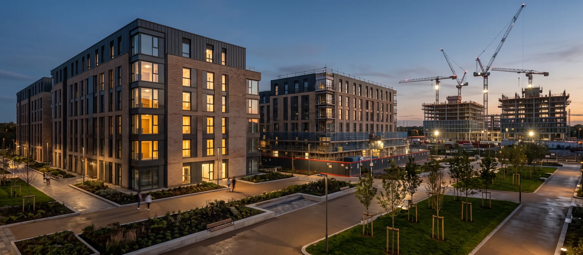Campus urbano de edificios contemporáneos con una residencia de estudiantes en primer término y oficinas en construcción al fondo, imagen ilustrativa
