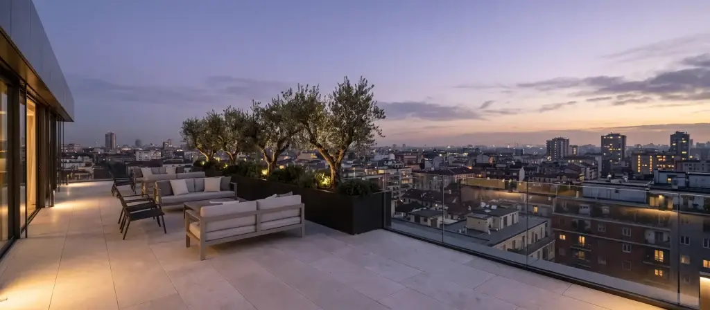 Terraza de un ático contemporáneo con mobiliario de exterior y vistas a los tejados de una ciudad al atardecer, imagen ilustrativa del mercado de residencias de marca